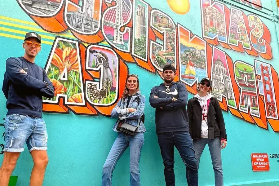 Trendy visitors pose in front of a 贝博体彩app mural.